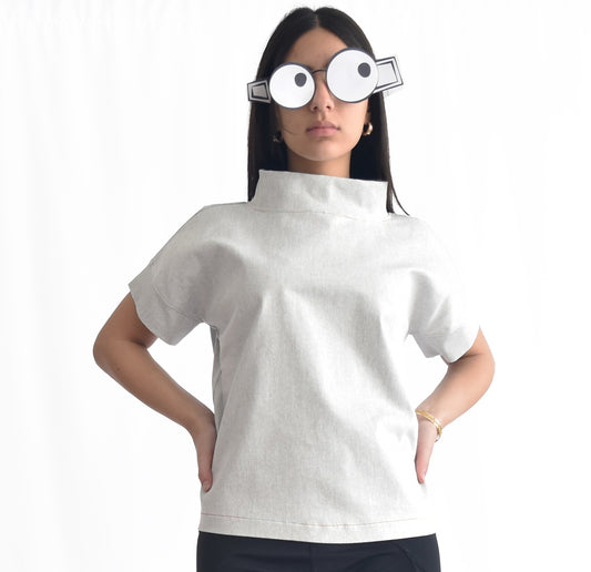 Woman wearing an off-white short-sleeve stretchy denim top with stand collar. The SheKnows Brand top has a structured, minimalist silhouette