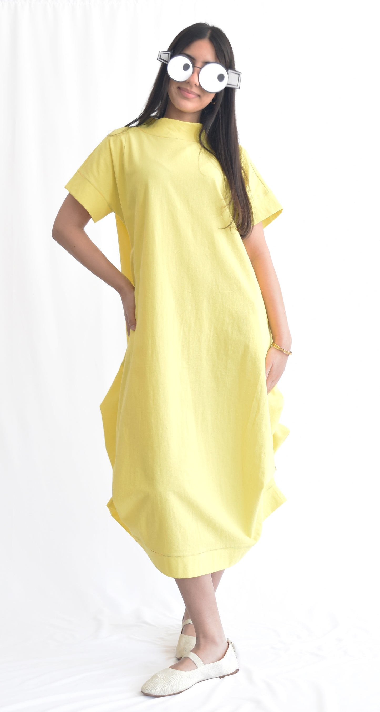 Woman wearing a yellow loose-fit midi dress with short sleeves and pockets, made from cotton poplin fabric from SheKnows Brand